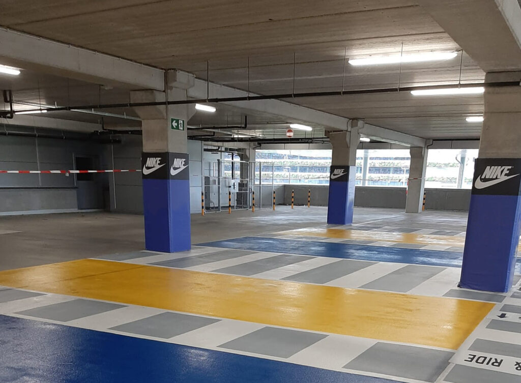 Columns in a parking garage with a Cingo Protective Wrap installed branded with the Nike logo