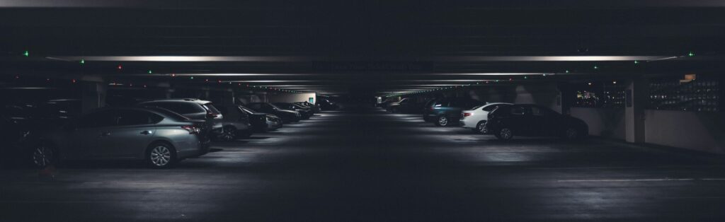 A long line of cars parked in a dimly lit parking garage
