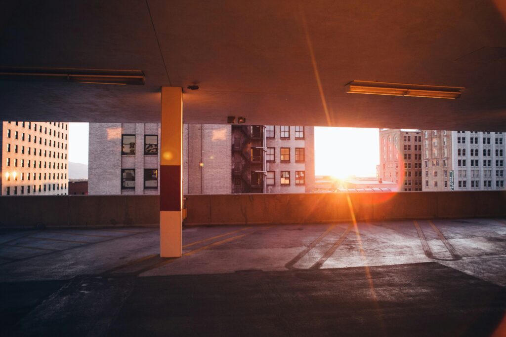 The sunset peaking between buildings as seen from inside a parking garage